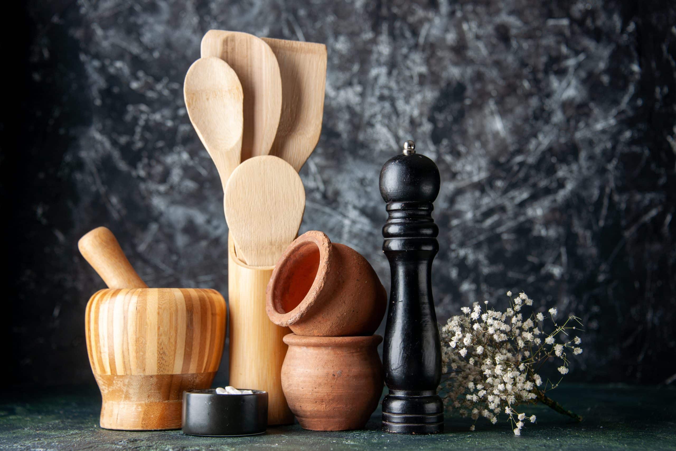 Utensilios de madera en la cocina. En la imagen vemos un conjunto de utensilios de madera: mortero, espátula, cuchara, etc. , con fondo negro.